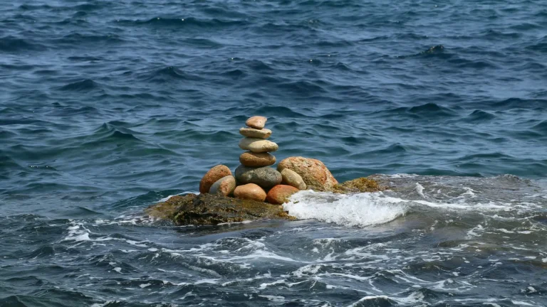 Balanced stack of stones on a rock surrounded by ocean water