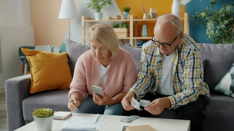 Senior couple sorting paperwork and cash together on a sofa