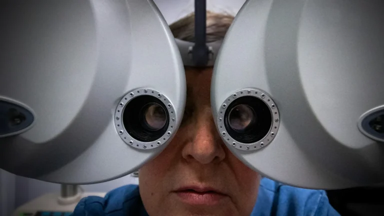 Person looking through a phoropter during an eye exam